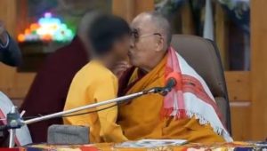 A still from the viral video in which the Dalai Lama kisses a young boy in front of others. Image Courtesy: @VickyDavilaH/Twitter